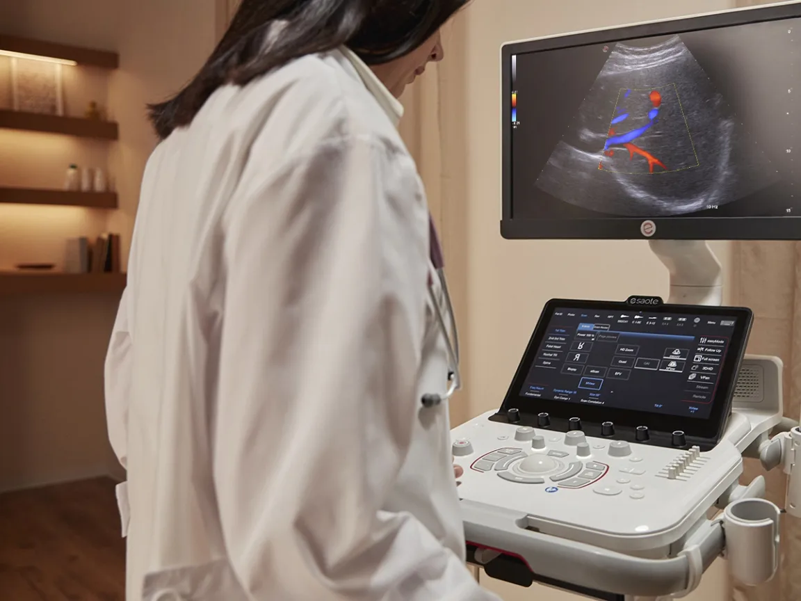 Clinician in a white lab coat operating an ultrasound machine showing a color Doppler scan on screen